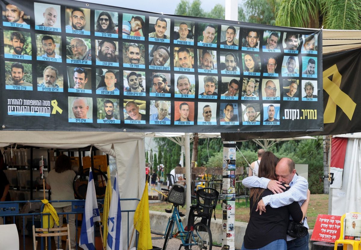 People hug next to banner with photos of hostages at the "Hostages square", after U.S. President Donald Trump announced that Israel and Hamas agreed on the first phase of a Gaza ceasefire, in Tel Aviv, Israel, October 9, 2025. REUTERS/Ronen Zvulun
