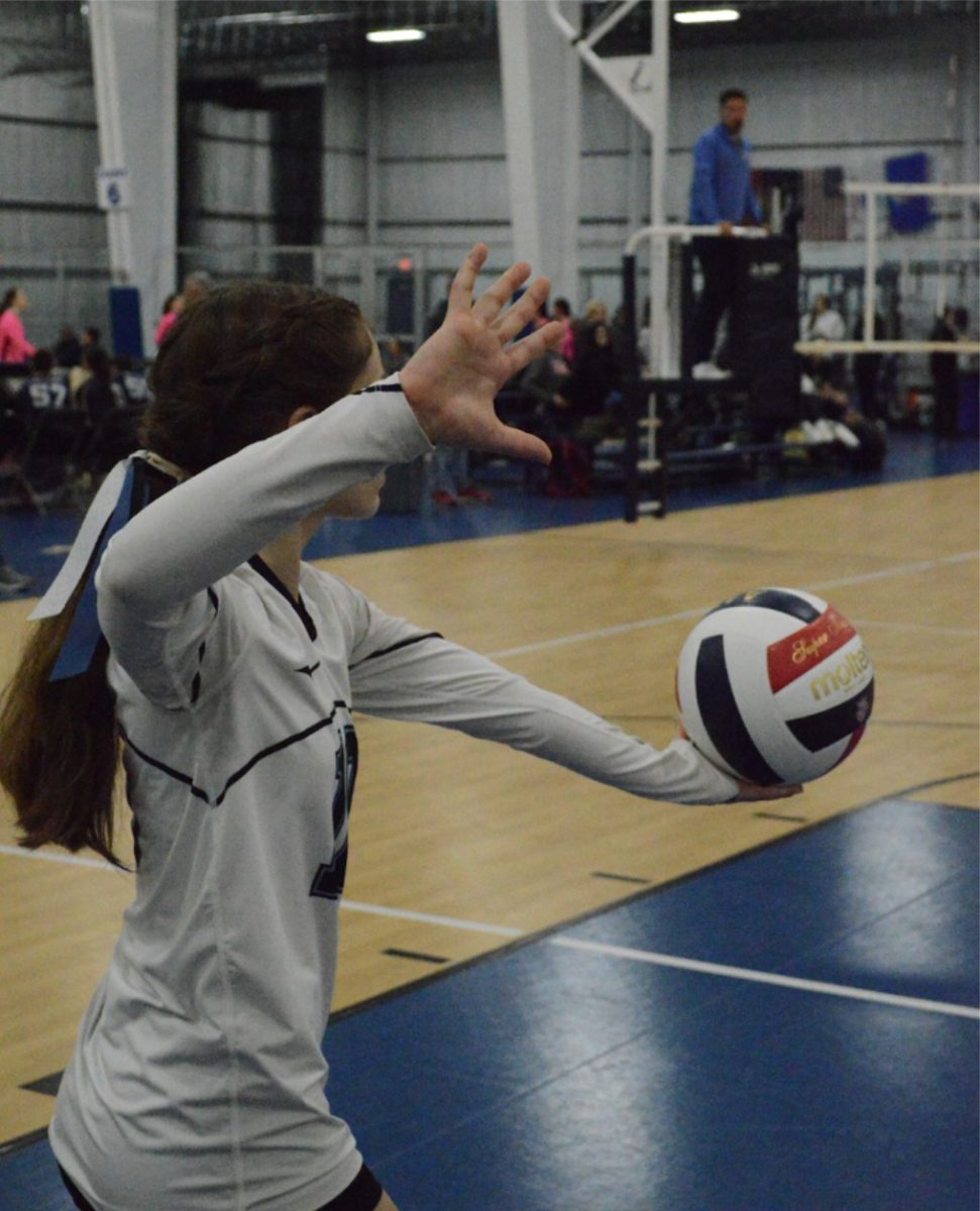 Sylvia Benyas steps up to serve for volleyball game.
